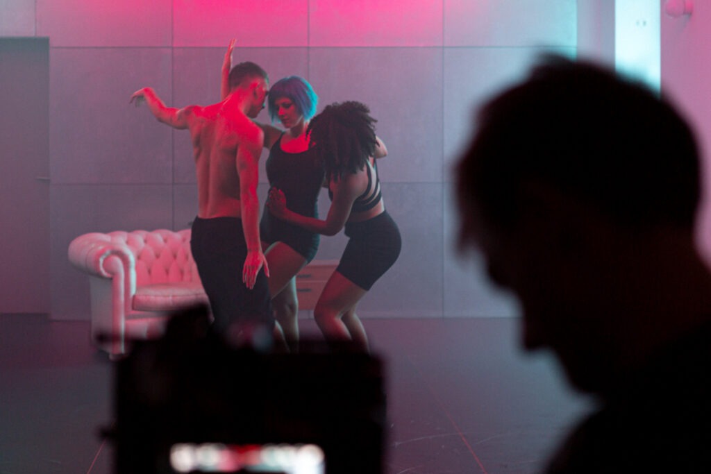Three dancers in a blue, pink room. The dancer in the middle is the singer PAENDA