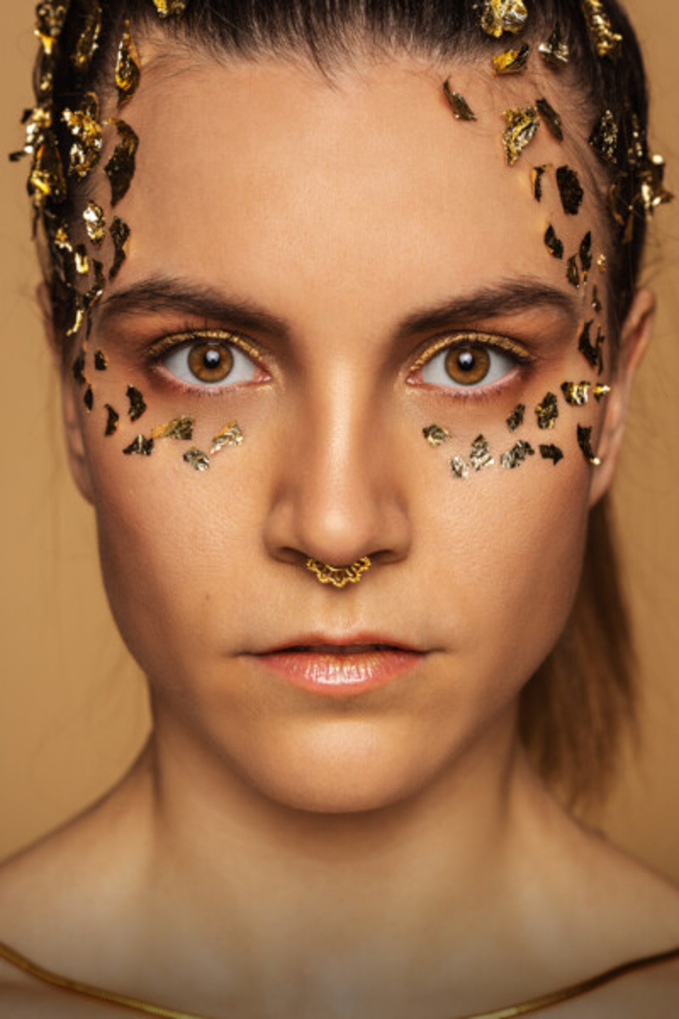 Gold_Fotoshooting_boxquadrat Portrait einer Frau mit goldenem make Up und Blattgold im Gesicht