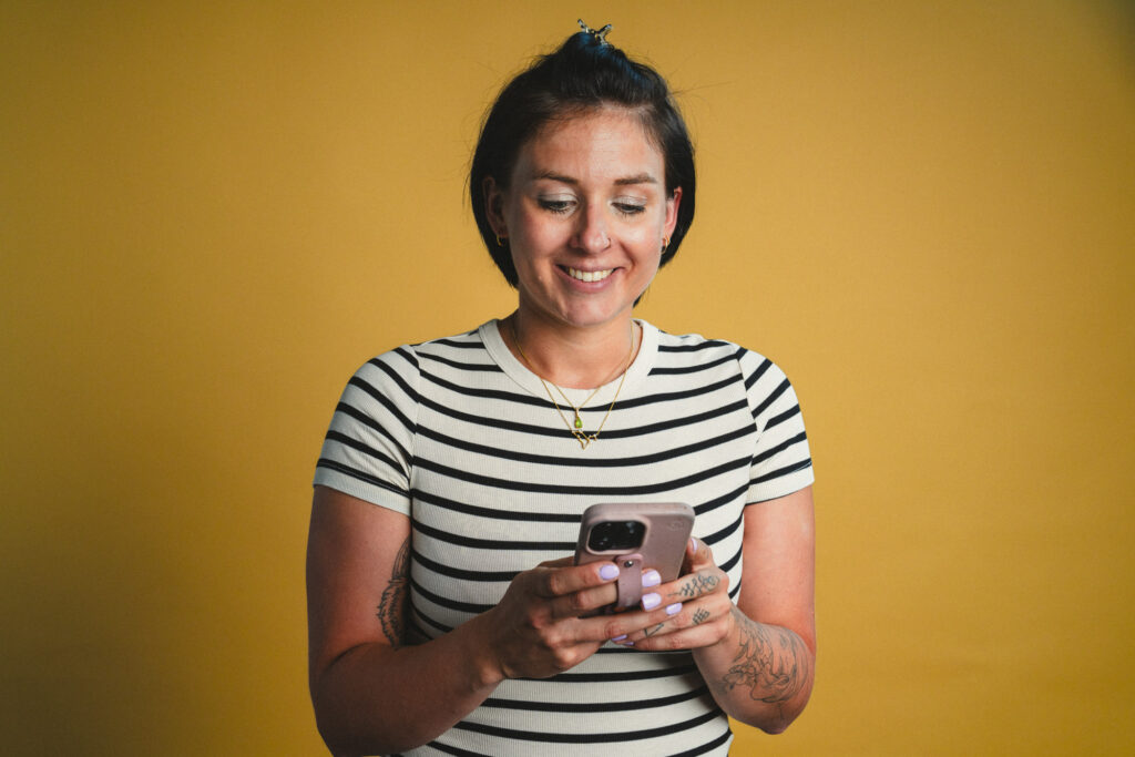 Portrait von Paula Sidorczuk, die lächelnd aufs Handy schaut, im boxquadrat Fotostudio 1160 Wien