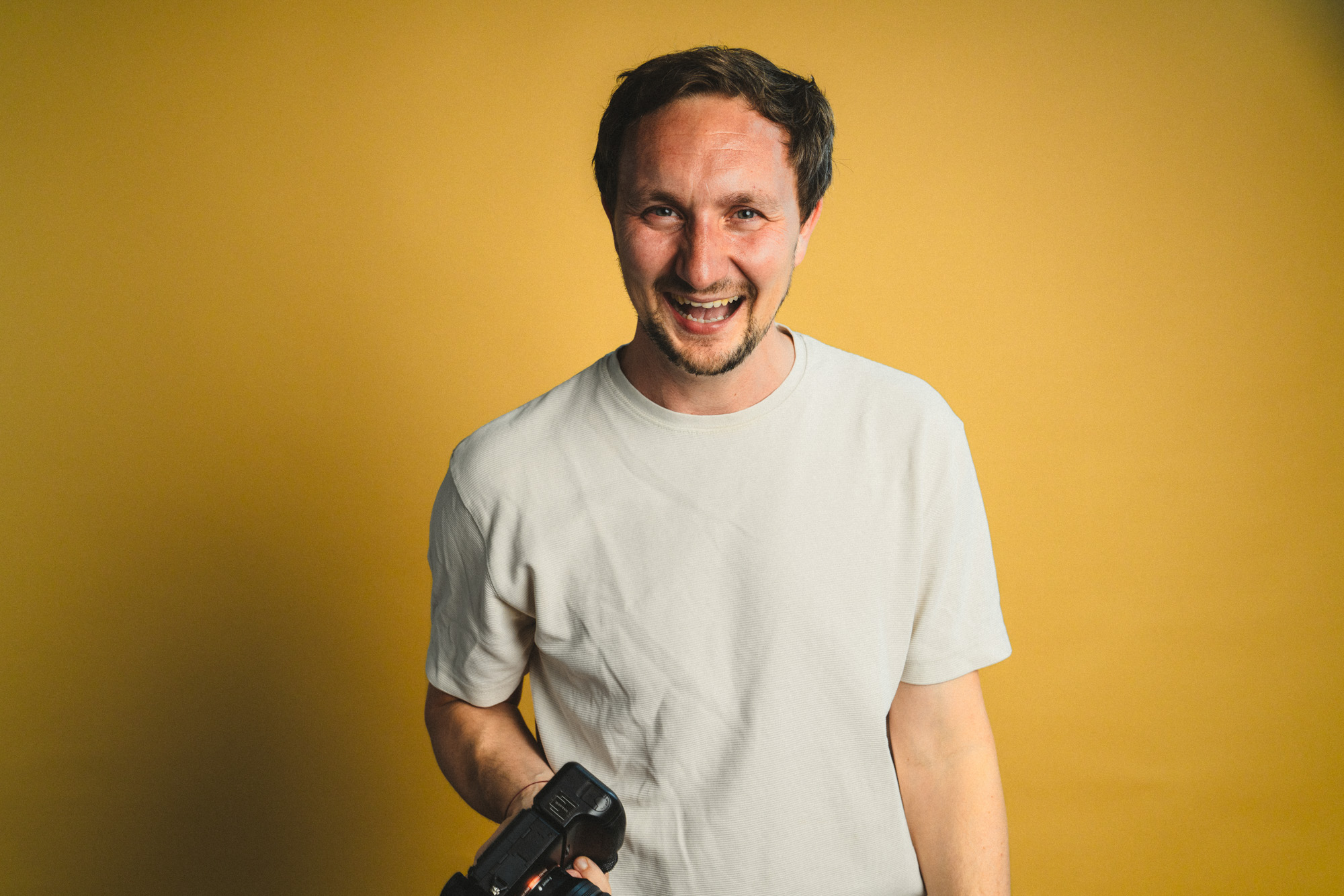 Portrait von Philipp Schulz lachend, mit Fotokamera in der Hand, im boxquadrat Fotostudio 1160 Wien