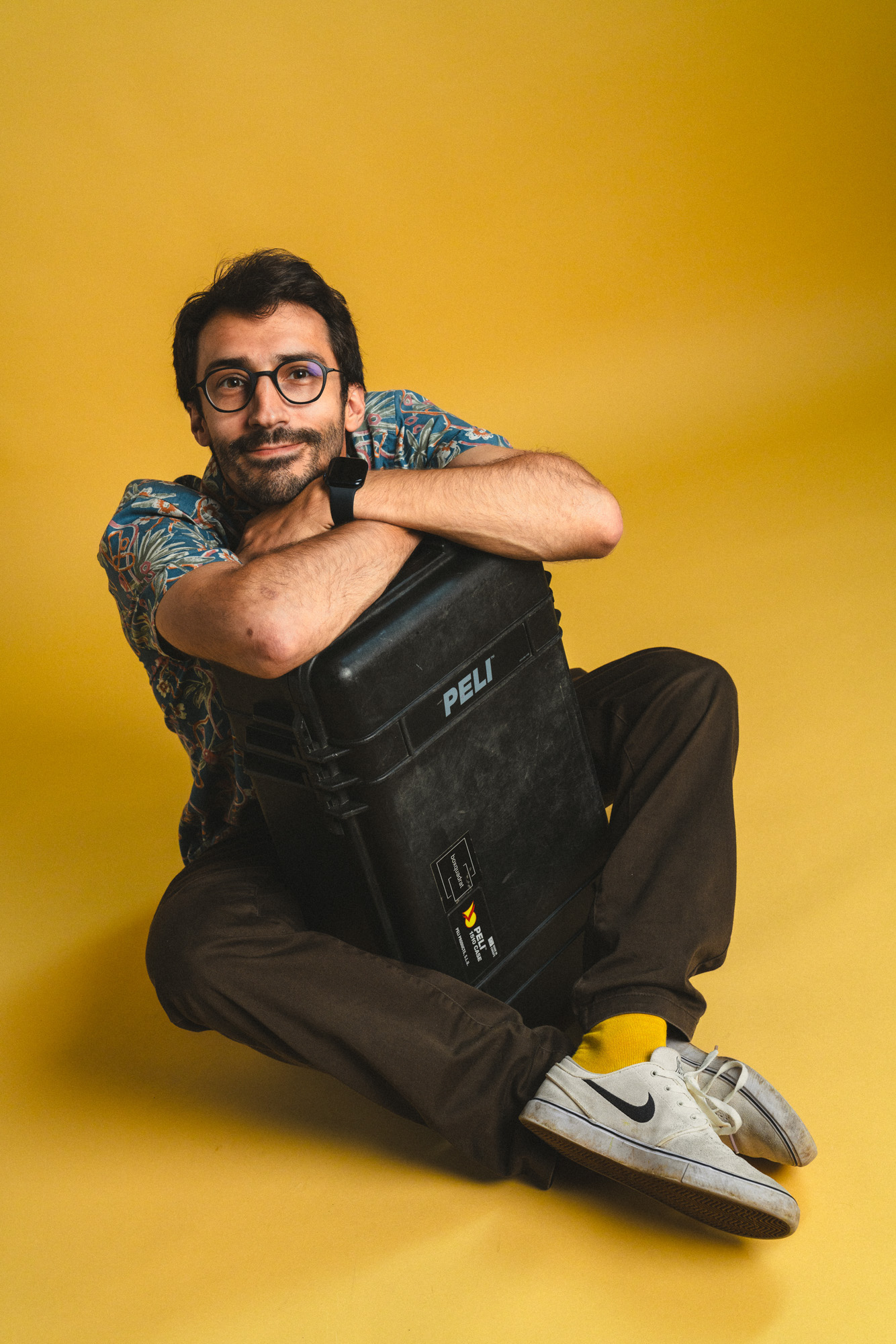 Aufsichtiges Foto von lachendem Jakob Grill, sitzend ein Pelicase umarmend, im boxquadrat Fotostudio 1160 Wien