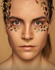 Portrait einer Frau mit goldenem make Up und Blattgold im Gesicht
