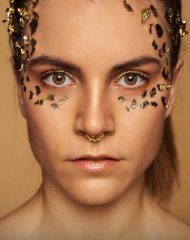 Portrait einer Frau mit goldenem make Up und Blattgold im Gesicht